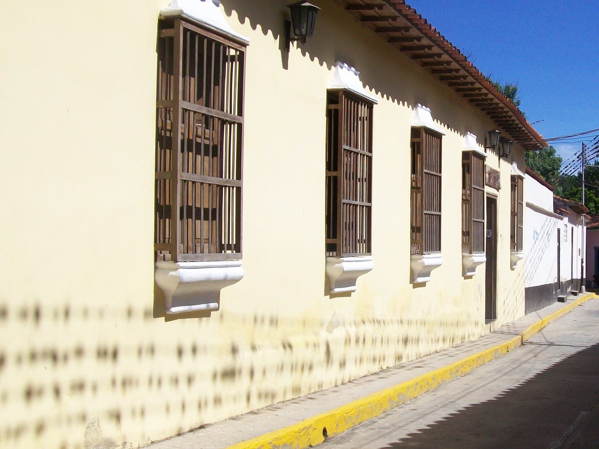 La casa: fachada colonial con ventanas de rejas de madera